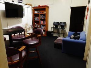 a living room with a couch and chairs and a tv at Meyenburg House in Mount Morgan