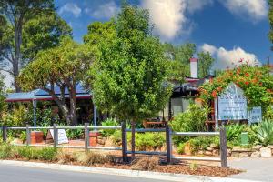 a tree in front of a building with a fence at Settlers Cottage in McLaren Vale