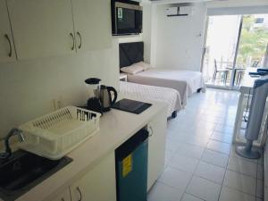 a small room with two beds and a kitchen with a counter at Acapulco Hotel y suites mediterrane in Acapulco