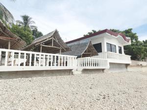a white house with a porch and a white fence at LUNA OSLOB TRAVELLERS INN - Beach Front in Oslob