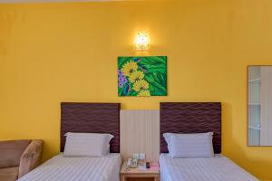 two beds in a room with yellow walls at Geopark Hotel Kuah Langkawi in Kuah