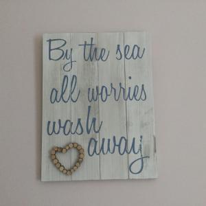 a sign that says by the sea all worries wasi wish always at Beachside Apartment in Bangor