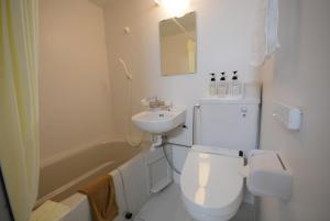 a white bathroom with a toilet and a sink at Kurobe Kanko Hotel in Omachi