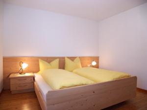 1 dormitorio con cama de madera y almohadas amarillas en Apartments Feldsagerhof, en Villabassa