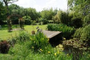 a garden with a wooden deck and a pond at Little Rose Cottage - Urlaub unter Reet zwischen den Meeren in Börm +6 photos
