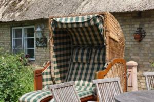 a wicker chair sitting in front of a house at Little Rose Cottage - Urlaub unter Reet zwischen den Meeren in Börm