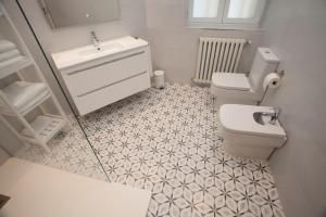 a bathroom with a white toilet and a sink at La Casa de Mozo in Ávila