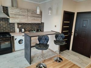 a kitchen with two bar stools and a sink at NEW Luxury Studio Apartment in Ivano-Frankivsʼk