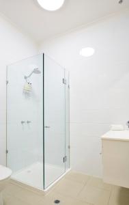 a white bathroom with a glass shower stall at Hotel Sophia in Melbourne