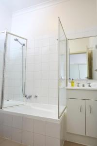 a white bathroom with a tub and a sink at Hotel Sophia in Melbourne
