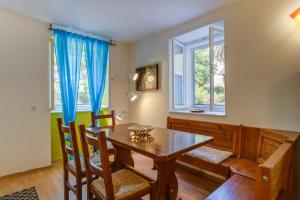 a dining room with a wooden table and two windows at BigBlue house Apartman Amelie in Veli Lošinj +9 photos