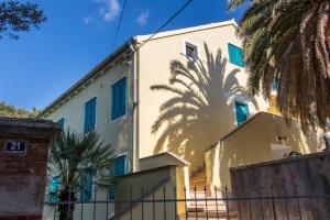 a building with a palm tree behind it at BigBlue house Apartman Amelie in Veli Lošinj