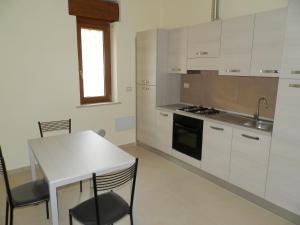 フィウミチーノにあるAppartamento Fiumicinoの白いキャビネット、テーブルと椅子付きのキッチンが備わります。