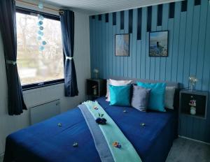 Schlafzimmer mit einem Bett mit blauer Bettwäsche und einem Fenster in der Unterkunft Urhanen in Gedser