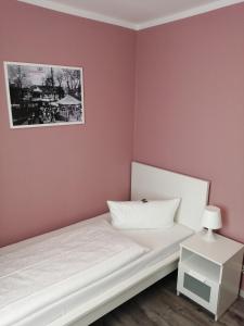 Un pequeño dormitorio con una cama blanca y paredes rosas. en Hotel Altes Badehaus en Bad Dürrenberg