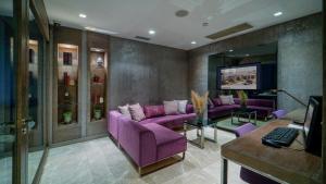ein Wohnzimmer mit lila Sofas und einem Fernseher in der Unterkunft The New Hotel Zeybek in Izmir