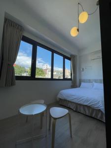 una camera da letto con un letto, due sedie e una finestra di Love Vacation Pourquoi pas a Città di Hualien