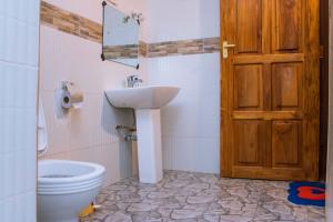 a bathroom with a toilet and a sink and a door at MANTIS LODGE & CAMPING SITE in Morogoro +30 photos