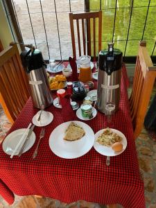 Morogoro的住宿－MANTIS LODGE & CAMPING SITE，红色桌布上带食物盘的桌子