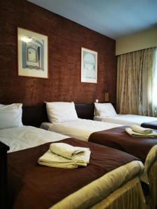 a hotel room with three beds with towels on them at Garni Hotel Oasis in Belgrade