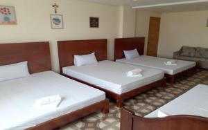 een kamer met drie bedden in een kamer bij WMV Hotel & Restaurant in Infanta
