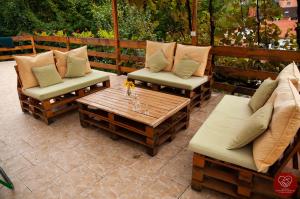 un patio con 2 sillas y una mesa de madera con almohadas en Guesthouse Edelnice, en Gornja Trepča