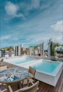 a swimming pool with chairs and a table on a roof at Manaíra Apart Hotel in João Pessoa