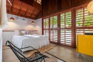 1 dormitorio con 1 cama en una habitación con ventanas en La Cozinha Bungalow en Barra Grande