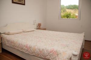 a white bedroom with a bed with a window at Guesthouse Edelnice in Gornja Trepča