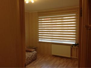 a bedroom with a window with blinds on it at Samson Apartments in Velikiy Novgorod