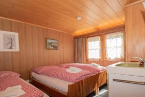 アデルボーデンにあるChalet Irisのベッド2台とシンクが備わる小さな客室です。
