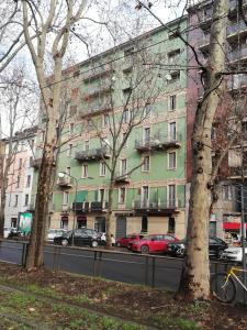 zielony budynek z samochodami zaparkowanymi przed nim w obiekcie Al 32 Apartment w Mediolanie