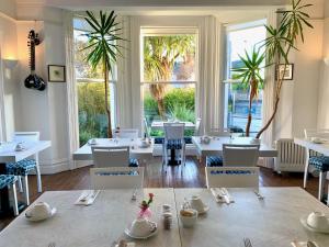 a dining room with white tables and chairs and windows at Derrin Guest House in Larne