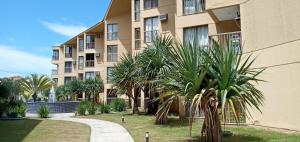 a building with palm trees in front of it at Sahy - Aldeia dos Reis, Condado - Apartamento Quarto e Sala in Mangaratiba