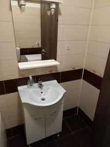 ein Badezimmer mit einem weißen Waschbecken und einem Spiegel in der Unterkunft Apartament 2 camere in Chiajna