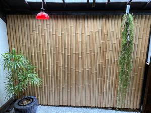 una recinzione di bambù con piante e luce rossa di YUMEJI Vintage Villa a Kyoto