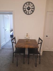 a dining room table with chairs and a clock on the wall at Eastgate Hideaway - central, luxury apartment on Chester's historic rows in Chester
