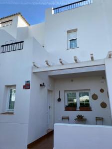een wit huis met een witte muur en ramen bij Precioso adosado rodeado de un entorno verde natural y muy cerca de la playa in Chiclana de la Frontera