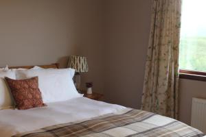 
a bed with a white comforter and pillows at Heatherbank Guest House in Strontian
