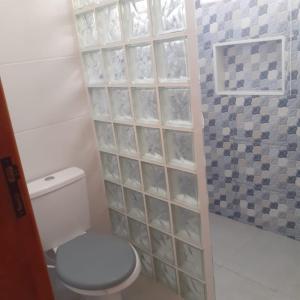 a bathroom with a toilet and a glass block wall at Casa do Sol in Praia Grande