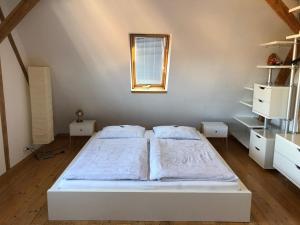 a white bedroom with two beds and a window at attraktives 2-Zimmer-Apartment mit Ausblick in Jena