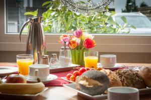 ein Tisch mit Frühstücksspeisen, Orangensaft und Blumen in der Unterkunft Hotel König in Remscheid