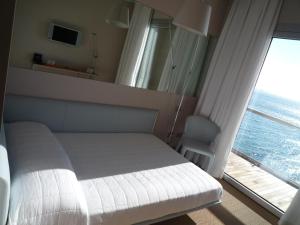 a bedroom with a white bed and a large window at Hotel Miramare - Adults Only in Trieste