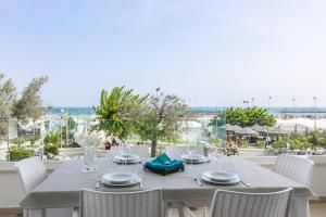 - une table avec des chaises blanches et une vue sur l'océan dans l'établissement CASA E MARE, à Senigallia