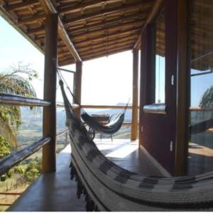 a hammock in a house with a view of the ocean at Chalés Beija-flor in Itambé do Mato Dentro