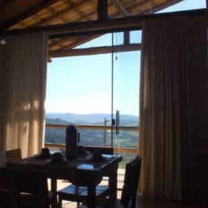 a dining room with a table and a large window at Chalés Beija-flor in Itambé do Mato Dentro