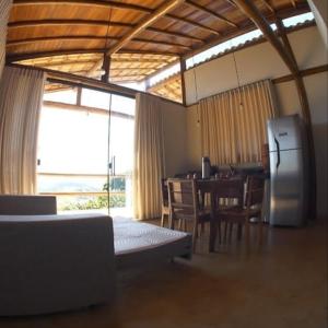 a room with a kitchen and a table and a refrigerator at Chalés Beija-flor in Itambé do Mato Dentro