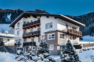 a building with snow covered trees in front of it at Apartpension Kappacher in Kaprun