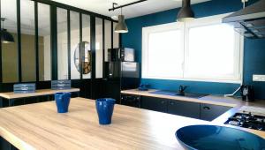 L'Atelier في فريهيل: مطبخ مع طاولة خشبية مع وجود أكواب زرقاء عليه
