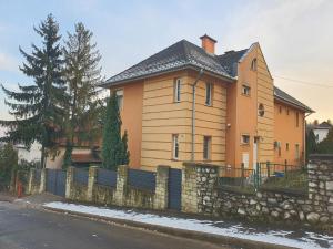 a house with a stone fence in front of it at Adel Apartman in Miskolc